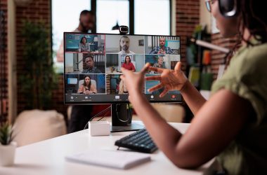 African american startup employee working from home gesturing in video conference with colleagues at desk. Small business owner talking with team in internet call on personal computer with webcam.